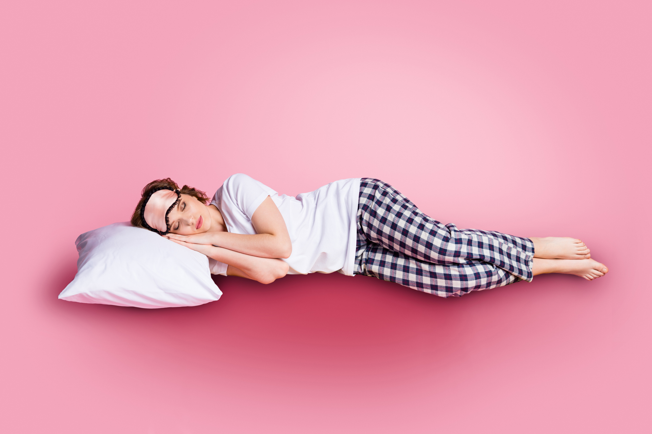 Vrouw in pyjama slapend roze achtergrond